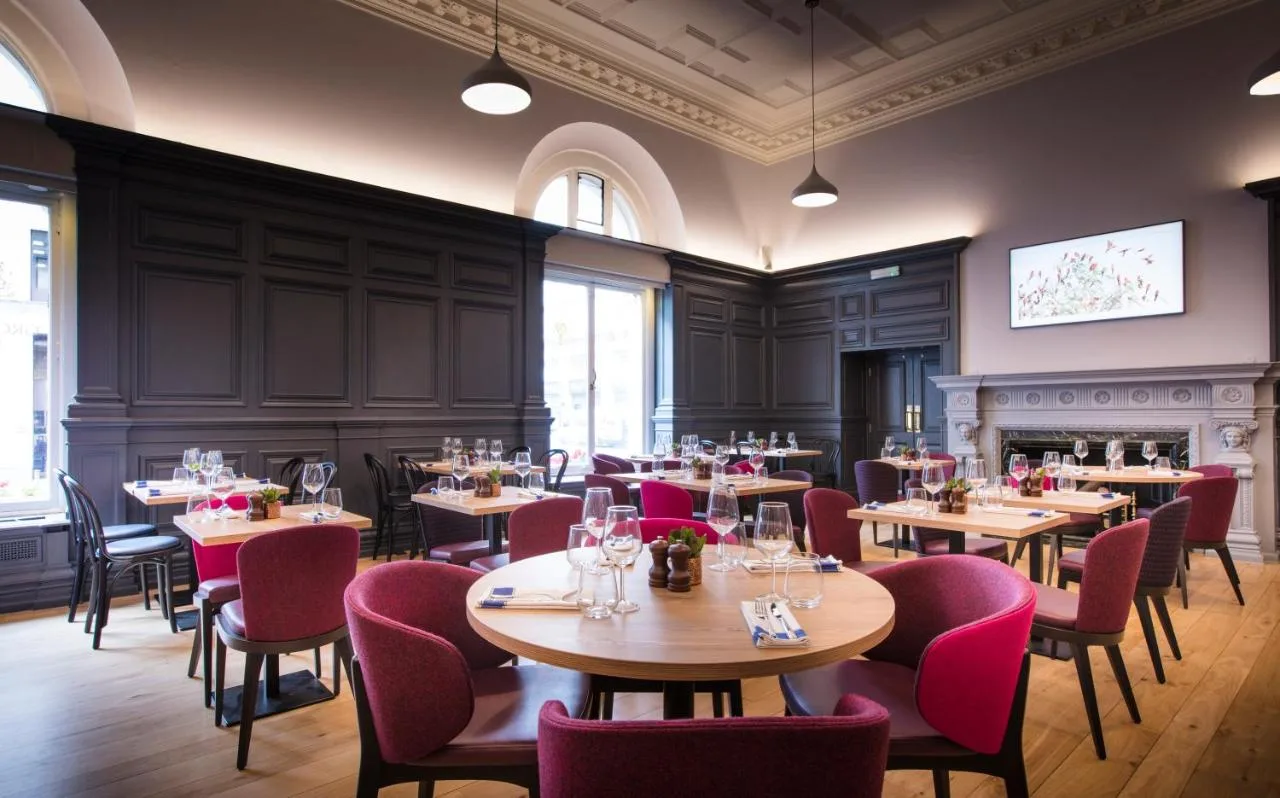 a restaurant with tables and chairs and a fireplace at The Clermont London, Victoria in London